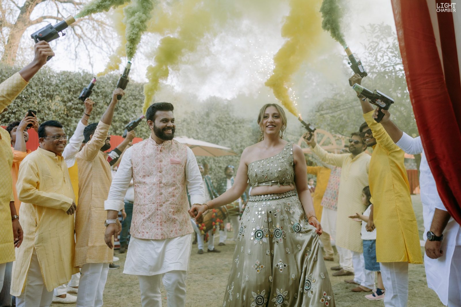Haldi under a canopy of pink and marigold, turmeric and petals in the air